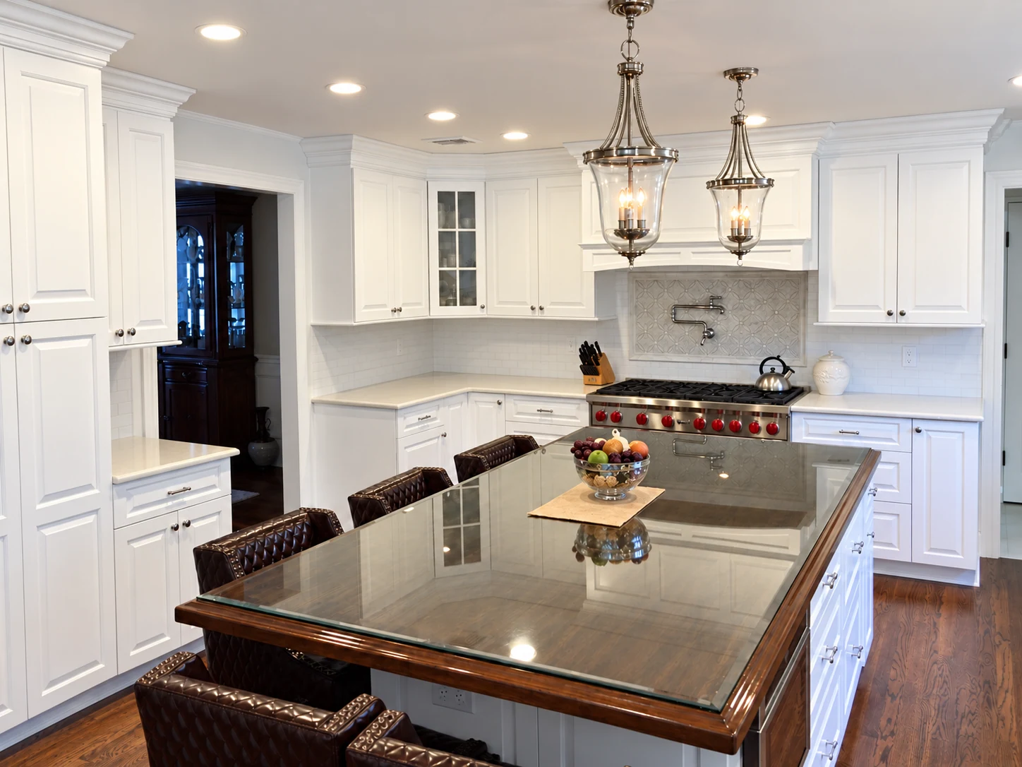 White kitchen with glass-topped wood-trim island and lantern pendants